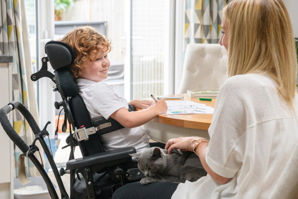 jongen in rolstoel met verzorgster