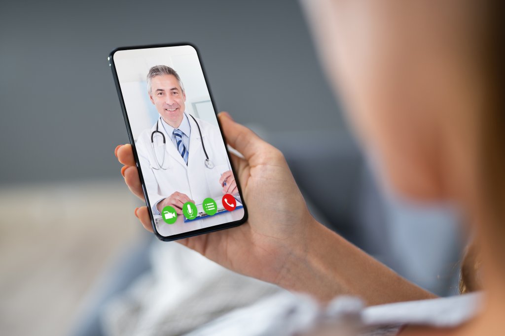 Een patiënt houdt een mobiele telefoon vast en communiceert met een arts.